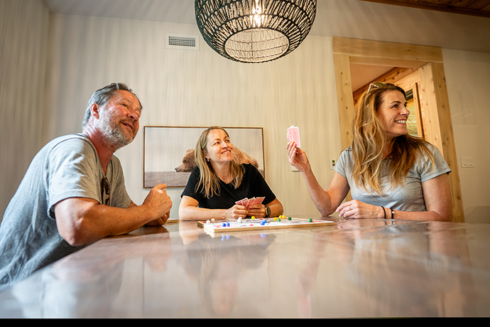 Three visitors play cards in the dinning room.