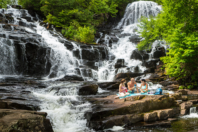 A family eats a picnic on the rocks at Waber Falls.