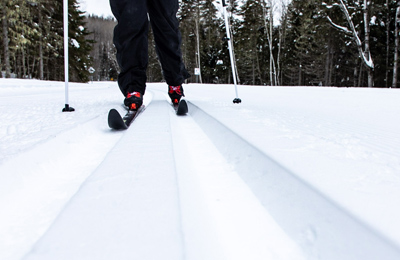 Cadrage d'un skieur à la hauteur des jambes, dans un sentier de ski de fond en nature.