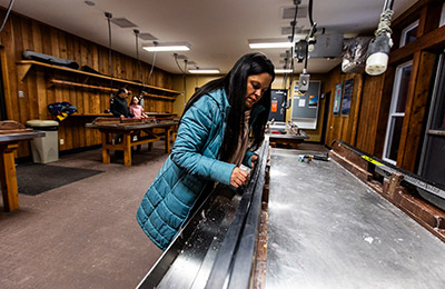 A person sets up her cross-country skis on a rack in a waxing room.