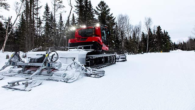 Une dameuse entretient un sentier de ski de fond.