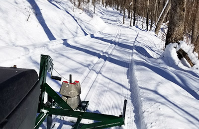 An all-terrain vehicle maintains a cross-country ski trail.