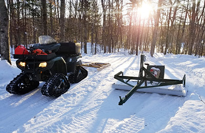 An all-terrain tracked vehicle with equipment for cross-country ski trail maintenance.