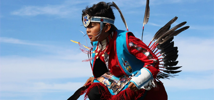 A young dancer of the First Nations wearing a traditional dress.