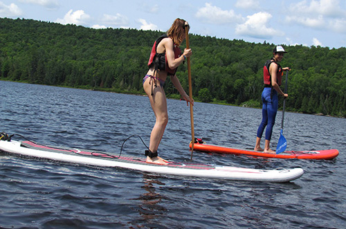 Deux jeunes filles pratiquent la planche à pagaie sur le lac Édouard
