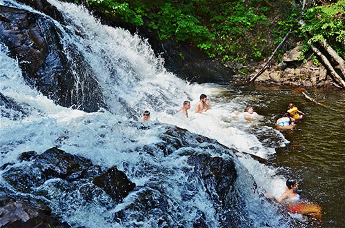 Des gens se baignent dans des cascades au pied de chutes