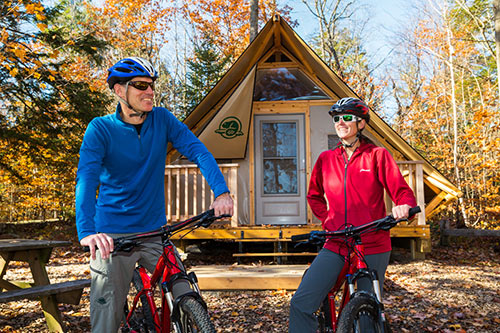 Un couple en vélo l'automne devant une tente oTENTik