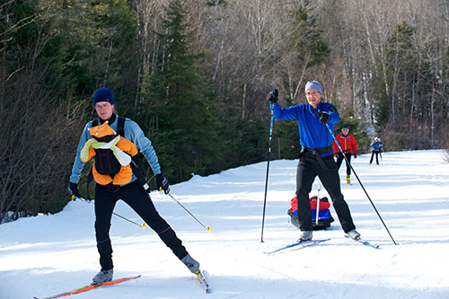 Jeune famille en ski de fond style libre sur un sentier damé