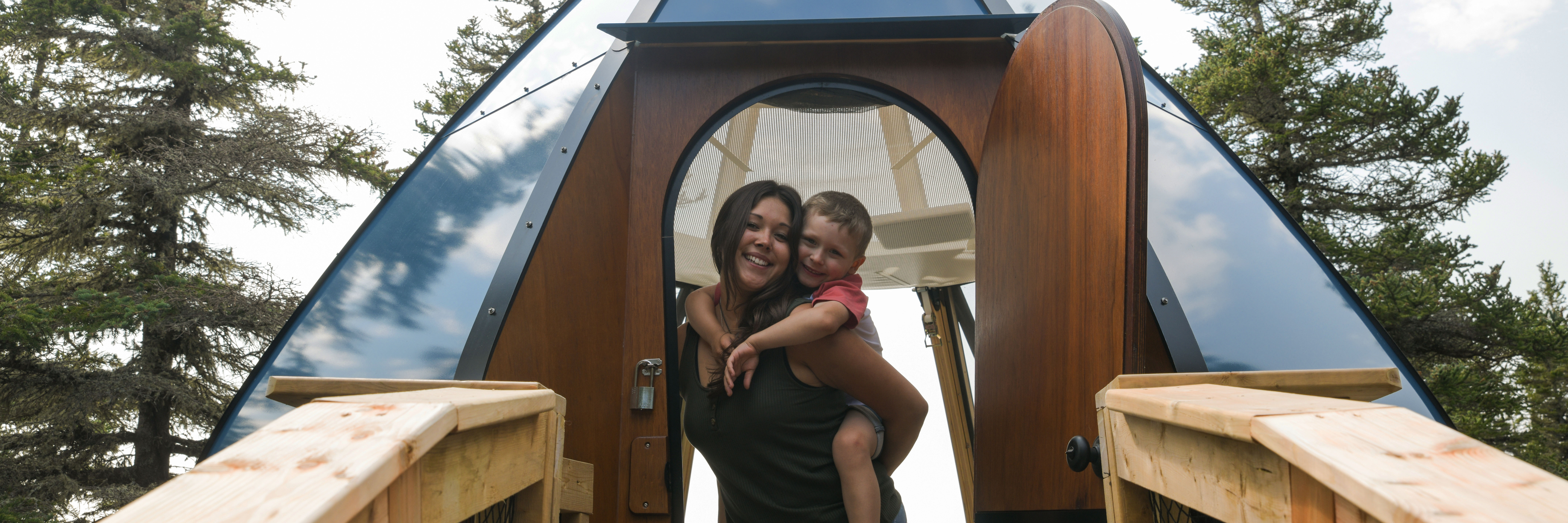 A blue Parks Canada Ôasis accommodation installed in the forest canopy with an access ramp. 