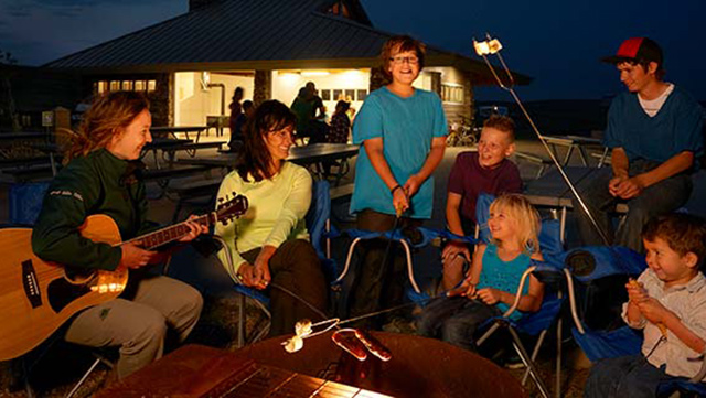 Familles chantant autour d’un feu de camp