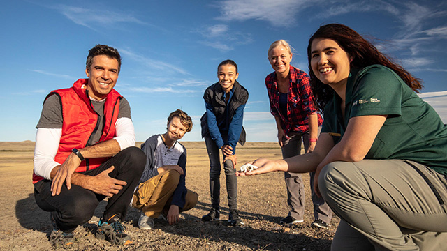 Grasslands National Park interpreter shows family educational props at a prairie dog colony Families singing around a campfire