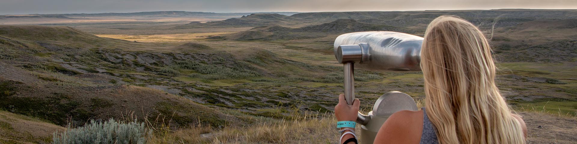 Une femme observe le paysage dans un télescope situé dans le bloc Ouest du parc national des Prairies.