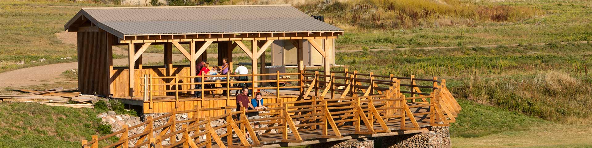  A group of visitors in shelters prepare a picnic for a couple observes the landscape.