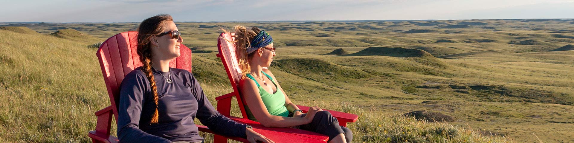 Visiteuses profitant de la vue sur les badlands depuis les chaises rouges installées dans le bloc Est du parc national des Prairies