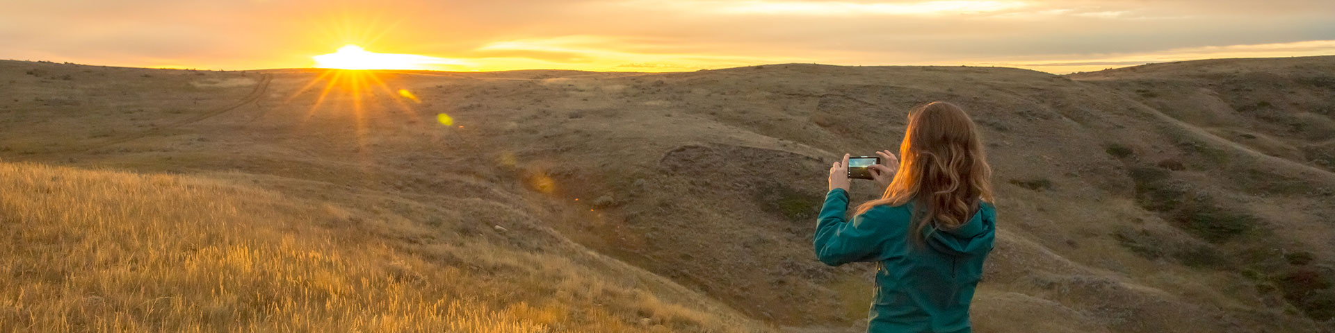 A woman photographing sunrise in September, at Grasslands National Park.