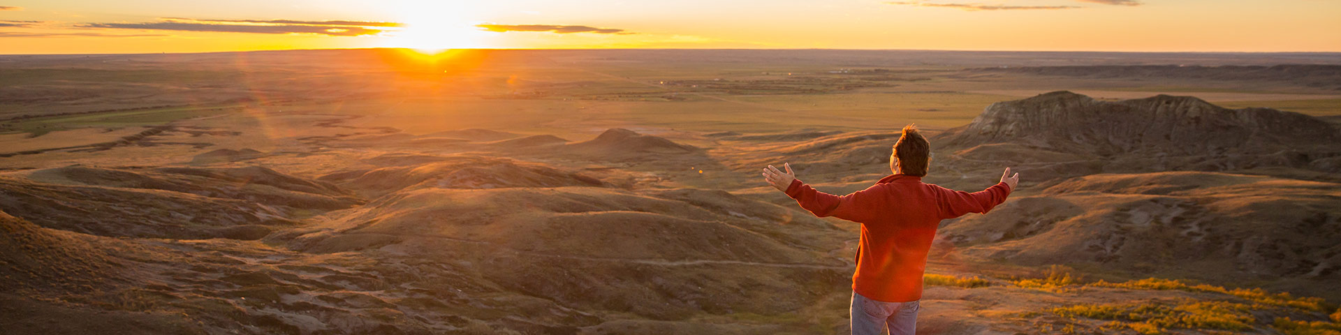 Un visiteur célèbre le coucher du soleil lors d'une randonnée sur le sentier de Butte-70-Mile du bloc Ouest, au parc national des Prairies.