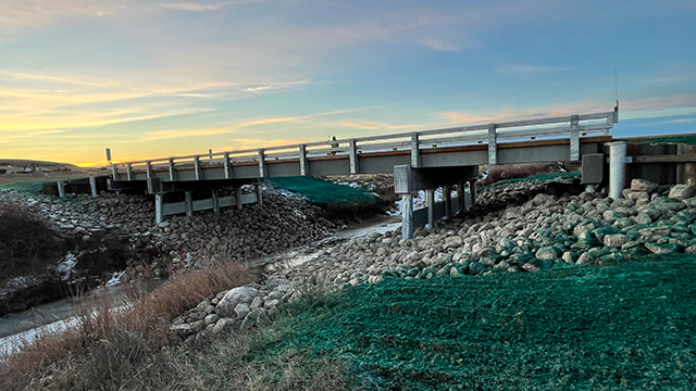 Side view of newly constructed bridge from riverbank. 