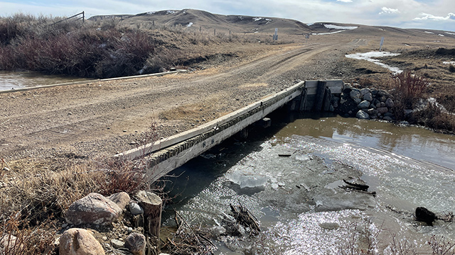 Water and ice flowing close to the underside of a wooden bridge. 