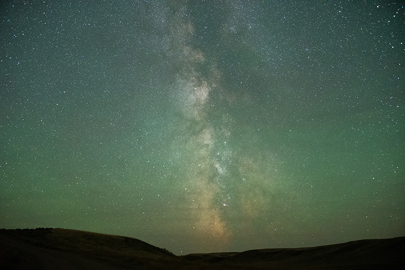 The brightness of the Milky Way Galaxy appears through the centre of a star filled sky in Grasslands National Park.