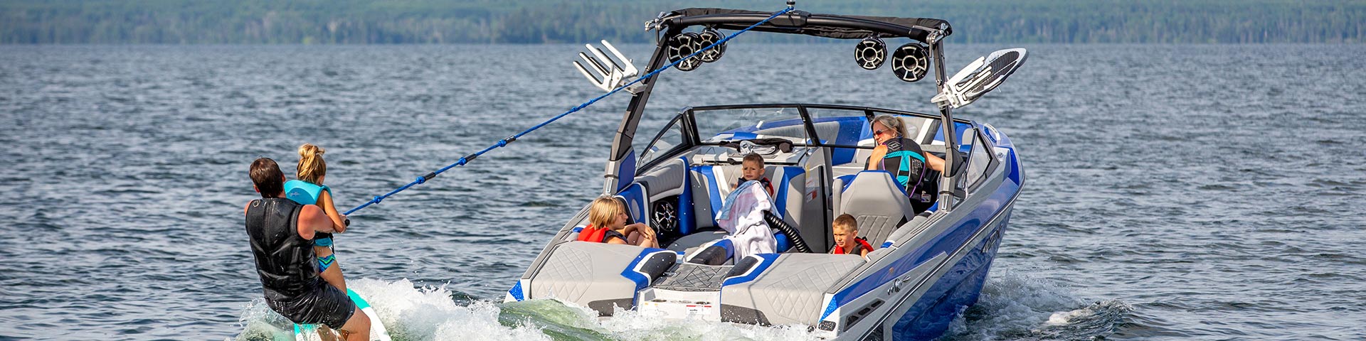A family wake surfing behind a boat on a summer day on Waskesiu Lake in Prince Albert National Park.