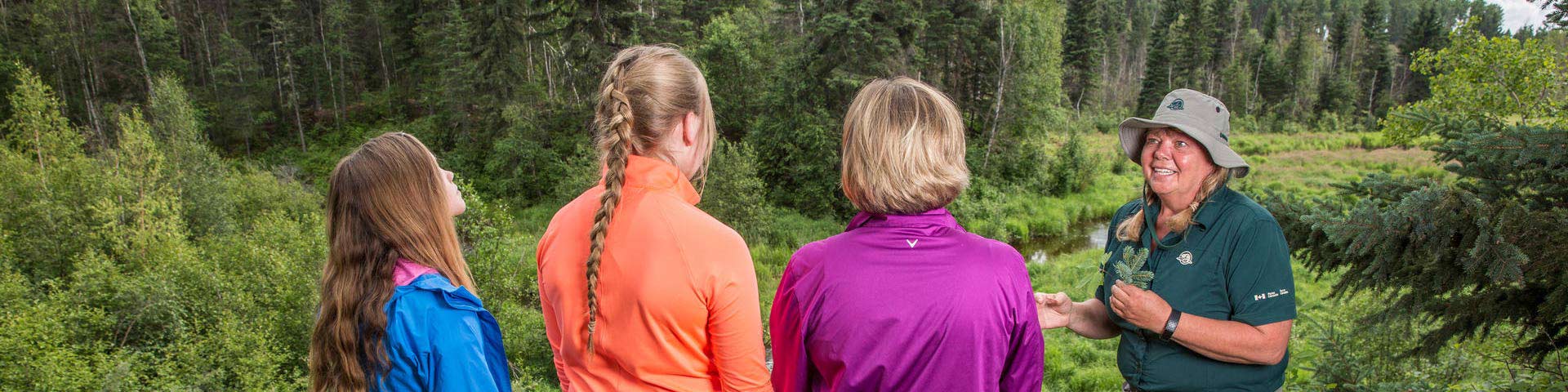 Visitors interact with a Parks Canada Interpreter at a viewpoint on the Mud Creek Trail in Prince Alberta National Park.