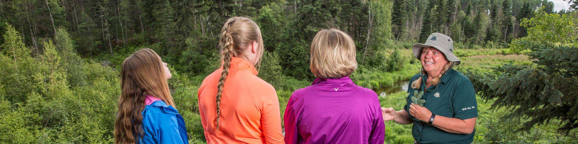 Des visiteurs interagissent avec une interprète de Parcs Canada à un point de vue sur le sentier du Ruisseau-Mud, au parc national de Prince Albert. 