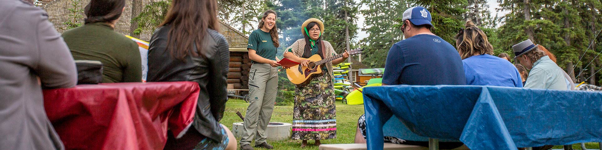 Des interprètes de Parcs Canada présentent un programme d’interprétation estival autour d’un feu de camp aux visiteurs du tipi du Grey Owl Centre, dans le lotissement urbain de Waskesiu, au parc national de Prince Albert. 