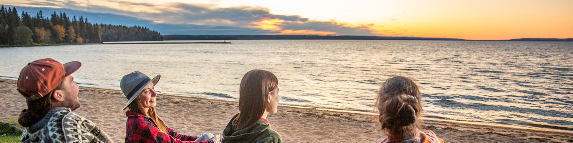 A group of visitors enjoying the sunset at the main beach in Waskesiu townsite in Prince Albert National Park.