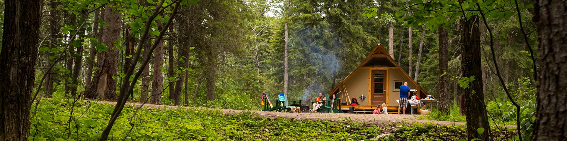 Une famille fait griller des guimauves sur un feu de camp à un site oTENTik sur le terrain de camping