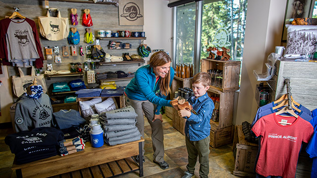 Des visiteurs regardent les marchandises de la boutique de Parcs Canada au centre d’accueil de Waskesiu, au parc national de Prince Albert. 