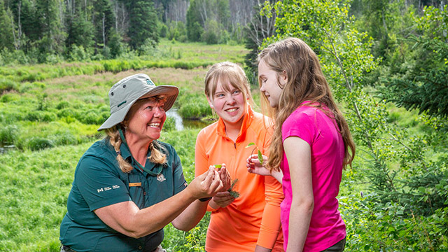 Visitors interact with a Parks Canada Interpreter at a viewpoint on the Mud Creek Trail in Prince Alberta National Park.