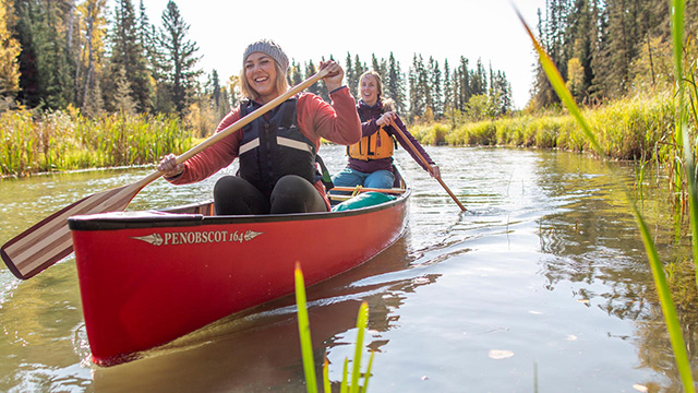 A group of young adult women on a canoe adventure on the Kingsmere River headed towards Kingsmere Lake in the Kingsmere Wilderness Area in Prince Albert National Park.