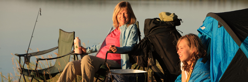 A women and her daughter enjoy the morning sunrise from their lakeside campsite.