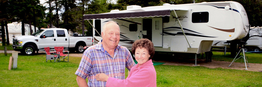 A couple pose for a picture in front of their RV.