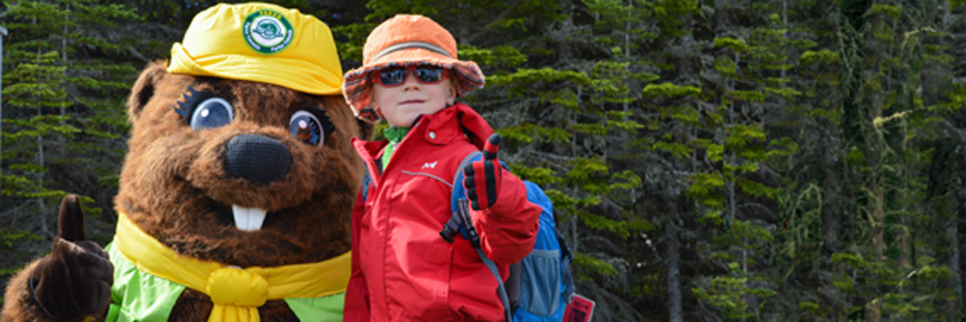 Parka, la mascotte de Parcs Canada pose avec un petit garçon portant des lunettes de soleil.