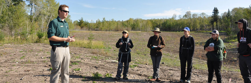 Un écologiste du parc discute avec un groupe d’étudiants sur un site de restauration d’un banc d’emprunt. 