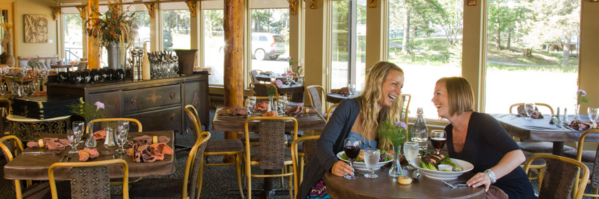 Two young ladies enjoy a meal at a table in an empty restaurant.