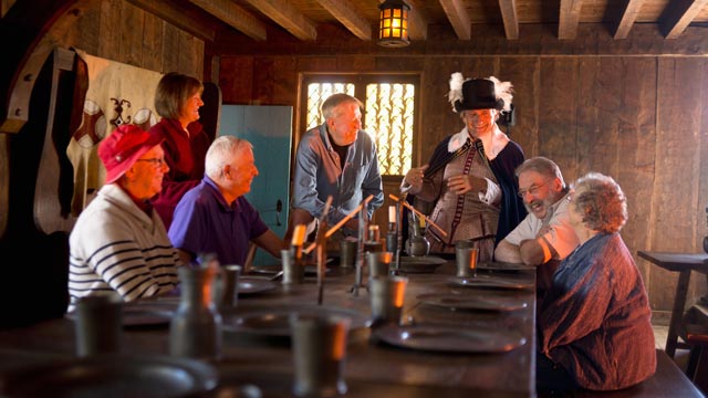 Un guide interprète en costume d'époque discute avec des visiteurs.