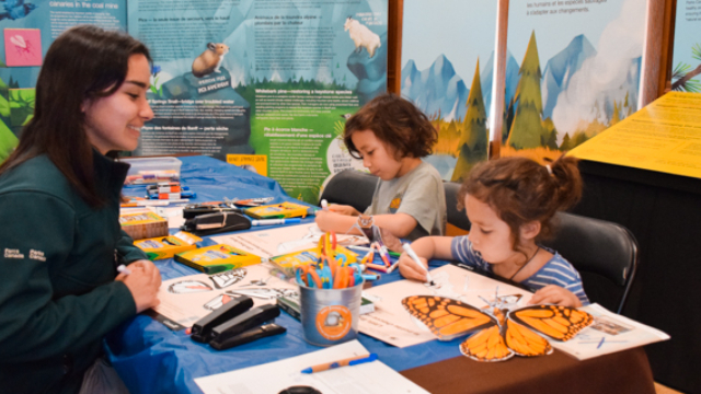 Une guide de Parcs Canada et des enfants font une activité d’art et d’artisanat.