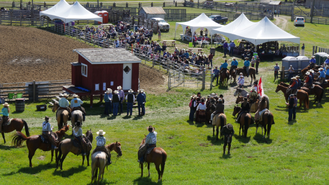 Tents, people on horses, and a crowd watching at the Bar U Ranch rodeo.