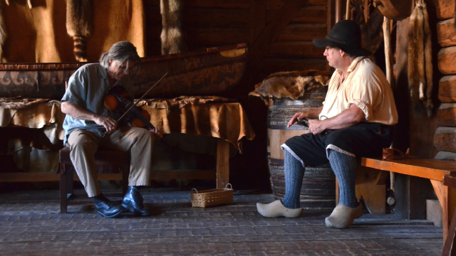 Un violoniste et un joueur de cuillères donnent un spectacle dans un bâtiment historique.