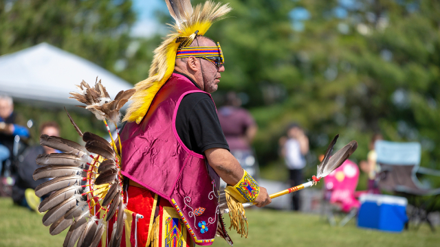 Une personne autochtone vêtue d’une tenue traditionnelle sur une aire de pique-nique.
