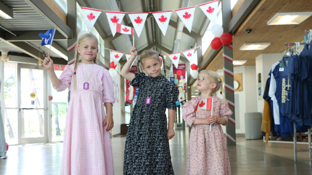 Trois enfants brandissent des drapeaux.