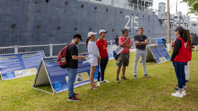 Un groupe de visiteurs et des bénévoles devant le destroyer de classe Tribal.