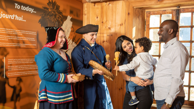 Un couple et un enfant discutent avec deux guides en costume d’époque.