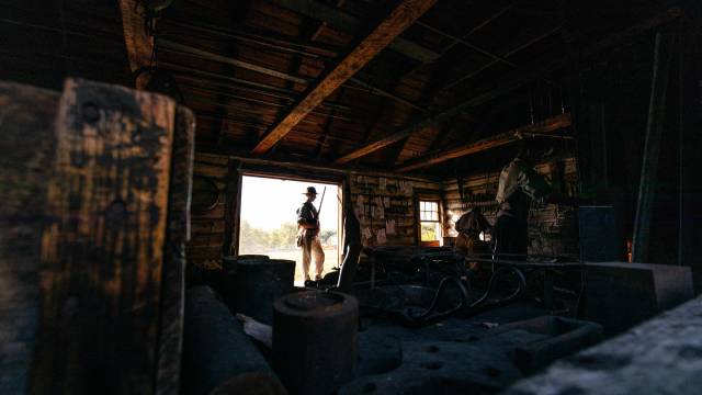 Un animateur historique se tient dans l'ombre, à l'intérieur d'un bâtiment historique de Lower Fort Garry.