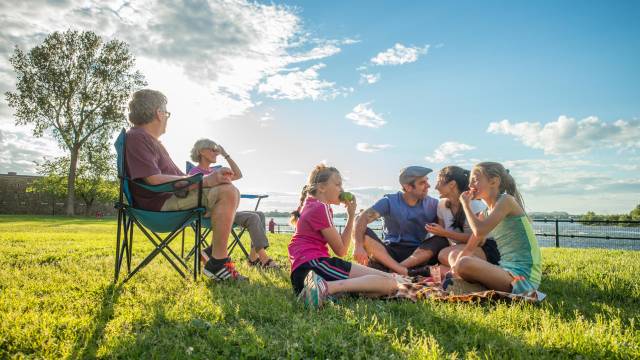 Une famille profite du soleil sur l’herbe en bordure de la rivière Richelieu au lieu historique national du Fort-Chambly