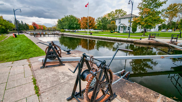 A view along a river with historic lock equipment in the foreground. 