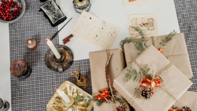 4 presents wrapped in recyclable packaging with a candle and various festive objects on a table.