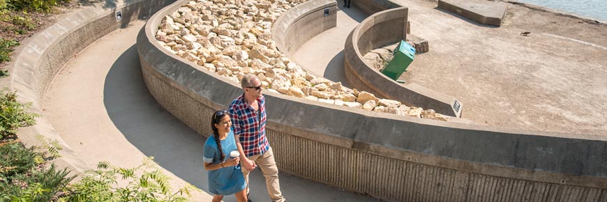 Visitors stroll along the riverwalk at Parks Canada Place.